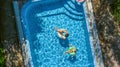 Aerial top view of children in swimming pool from above, happy kids swim on inflatable ring donuts and have fun in water Royalty Free Stock Photo