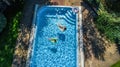 Aerial top view of children in swimming pool from above, happy kids swim on inflatable ring donuts and have fun in water Royalty Free Stock Photo