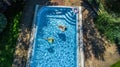 Aerial top view of children in swimming pool from above, happy kids swim on inflatable ring donuts in water on family Royalty Free Stock Photo