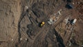 Aerial top view of a construction site or country dump with yellow excavator or bulldozer, heavy equipment, drone photo