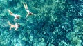 Aerial top view of family snorkeling from above, mother and kids snorkelers swimming in a clear tropical sea water, Thailand