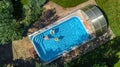 Aerial top view of family in swimming pool from above, happy mother and kids swim on inflatable ring donuts and have fun in water