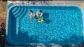 Aerial top view of family in swimming pool from above, mother and kids swim and have fun in water on family vacation