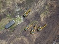 Aerial top view of four yellow crawler excavators standing on ground near the construction site and waiting for the working day to Royalty Free Stock Photo