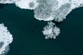 Aerial top view of frozen lake in wintertime. snow-covered shore and small island with trees Royalty Free Stock Photo