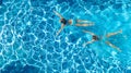 Aerial top view of girls in swimming pool water from above, active children swim, kids have fun on tropical family vacation