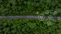 Aerial top view of green electric vehicle car driving over straight forest road, EV car electric vihicle car on forest road with