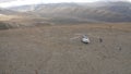 Aerial top view of a helicopter on dry ground arrived to rescue a small group of people. Clip. Saving tourists lost in