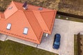 Aerial top view of house metal shingle roof with attic windows and black car on paved yard