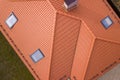 Aerial top view of house metal shingle roof, brick chimneys and small plastic attic windows. Roofing, repair and renovation work
