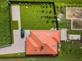 Aerial top view of house shingle roof with attic windows and black car on paved yard with green grass lawn Royalty Free Stock Photo