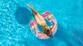 Aerial top view of little girl in swimming pool from above, kid swims on inflatable ring donut , child has fun in water