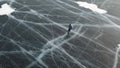 Aerial top view of a man ice skating outdoors on frozen water reservoir. Clip. Male tourist ice skating on frozen lake