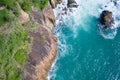 Aerial top view of ocean`s beautiful waves and rocky coast with greenery