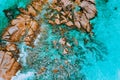 Aerial top view of ocean waves hitting granite rocks on the beach in La Digue, Seychelles