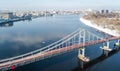 Aerial top view of pedestrian Park bridge in winter and Dnieper river from above, snow Kyiv cityscape, city of Kiev skyline Royalty Free Stock Photo