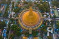 Aerial top view of Phra Pathommachedi temple at sunset. The golden buddhist pagoda with residential houses, urban city of Nakorn