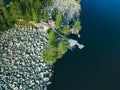 Aerial top view of red log cabin or cottage with a sauna in a green forest near a lake with rocky coast in Finland Royalty Free Stock Photo