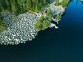 Aerial top view of red log cabin or cottage with a sauna in a green forest near a lake with rocky coast in Finland Royalty Free Stock Photo