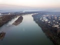 Aerial top view of river flowing through town. Rural landscape of residential house roofs, roads and tree tops on spring or autumn Royalty Free Stock Photo