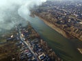 Aerial top view of river flowing through town. Rural landscape of residential house roofs, roads and tree tops on spring or autumn Royalty Free Stock Photo