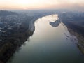 Aerial top view of river flowing through town. Rural landscape of residential house roofs, roads and tree tops on spring or autumn Royalty Free Stock Photo