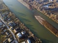 Aerial top view of river flowing through town. Rural landscape of residential house roofs, roads and tree tops on spring or autumn Royalty Free Stock Photo