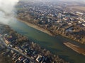 Aerial top view of river flowing through town. Rural landscape of residential house roofs, roads and tree tops on spring or autumn Royalty Free Stock Photo