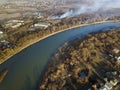 Aerial top view of river flowing through town. Rural landscape of residential house roofs, roads and tree tops on spring or autumn Royalty Free Stock Photo