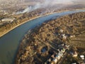 Aerial top view of river flowing through town. Rural landscape of residential house roofs, roads and tree tops on spring or autumn Royalty Free Stock Photo