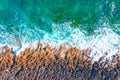 Aerial top view of sea waves hitting rocks on the beach