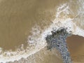 Aerial top view of sea waves hitting rocks on the beach in Pantai cahaya bulan