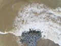 Aerial top view of sea waves hitting rocks on the beach in Pantai cahaya bulan