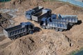 Aerial top view of several dump trucks unloading sand at a construction site. Industrial panorama. Royalty Free Stock Photo