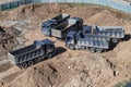 Aerial top view of several dump trucks unloading sand at a construction site. Industrial panorama. Royalty Free Stock Photo