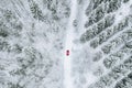 Aerial top view of snow covered forest with winter road and red car Royalty Free Stock Photo