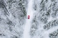 Aerial top view of snow covered forest with winter road and red car Royalty Free Stock Photo