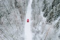Aerial top view of snow covered forest with winter road and red car Royalty Free Stock Photo