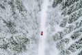 Aerial top view of snow covered forest with winter road and red car Royalty Free Stock Photo