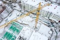 Aerial top view of tall tower crane working at construction site in winter Royalty Free Stock Photo