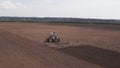 Aerial top view of tractor cutting furrows in farm field for sowing farm tractor with rotary harrow plow preparing land