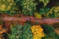 Aerial top view travel drive autumn road in yellow forest, concept of trip by red car Royalty Free Stock Photo