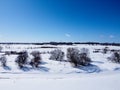 Aerial top view of trees next to a frozen river in winter , surrounded by snow. Kanata neighborhood seen in the