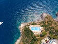 Aerial top view. Villa with a swimming pool by the sea. Steep rocky shore. Tourism and vacation concept. The motor boat moves fast