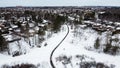 Aerial top view of a winding foot path in winter , surrounded by snow. Kanata neighborhood can be seen in the background
