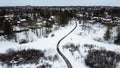 Aerial top view of a winding foot path in winter , surrounded by snow. Kanata neighborhood can be seen in the background