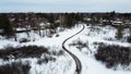 Aerial top view of a winding foot path in winter , surrounded by snow. Kanata neighborhood can be seen in the background