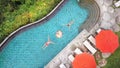 Aerial Top View: Young Couple with Floating Breakfast in Swimming Pool. Man and Woman Swim Towards Each Other. Tropical Vacation Royalty Free Stock Photo