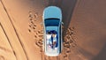 AERIAL. Top view of young couple relaxing on the car's roof at the desert. Royalty Free Stock Photo