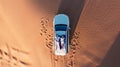 AERIAL. Top view of young couple relaxing on the car's roof at the desert. Royalty Free Stock Photo